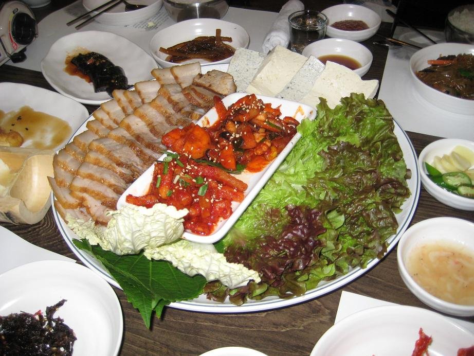 Sliced bossam, Korean boiled pork belly, served with lettuce wraps and radish salad